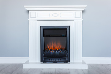 White wooden decorative electric fireplace with a beautiful burning flame. Interior photo on gray background. - 261520455
