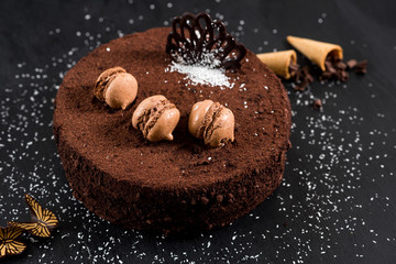 Sweet chocolate cake on the black wooden background