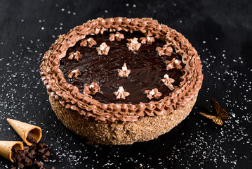 Sweet chocolate cake on the black wooden background
