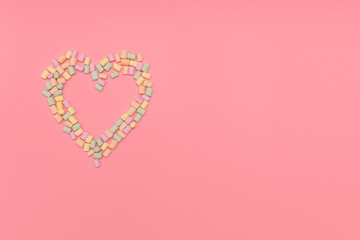 Heart of multicolored marshmallows isolated on pink background. Love, congratulation concept. Banner, postcard. Top view, copy space.