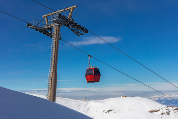 A red cable car cabin in the winter sports region at Granada in the Sierra Navada in front of blue...