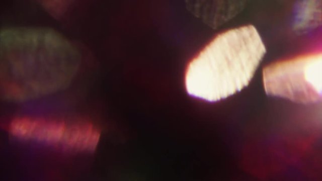Multicolored holographic light spots shines randomly in the dark. Pink hue, natural bokeh. Prores codec 4k.