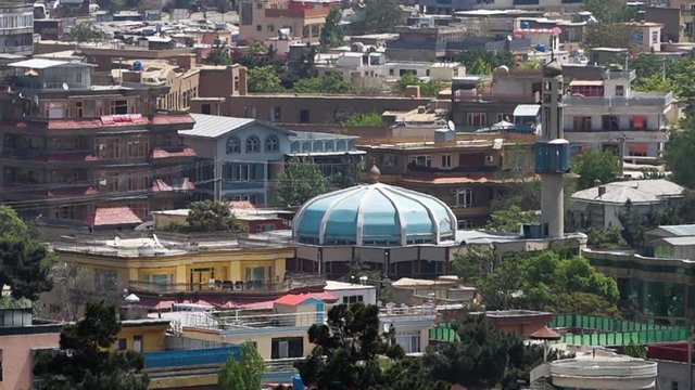 A steady, medium shot of conglomerated buildings during a very hot summer day.