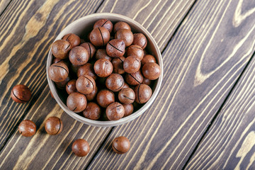 Macadamia nuts in bowl on a wooden table with copy space. Top wiew.