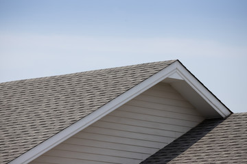 Roof shingles on top of the house against blue sky with cloud, dark asphalt tiles on the roof background © Rattanachat