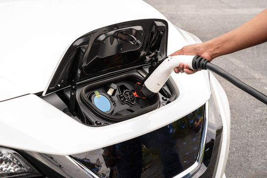 African-American Woman Plugging in an Electric Car