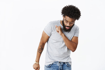 Bearded african american guy showing dance moves as having fun enjoying music, celebrating success and win waving head looking down at feet carefree and cool, posing delighted over gray background