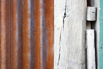 Closeup on texture of old rusty corrugated roof sheet and wooden column painted in white color with green concrete wall for abstract graphic background.
