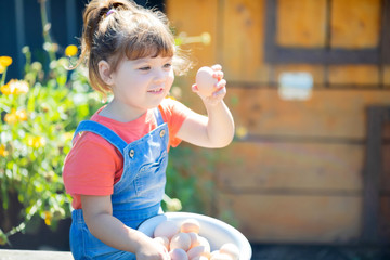 Adorable little girl holding basket full of white and brown raw eggs © Alinsa