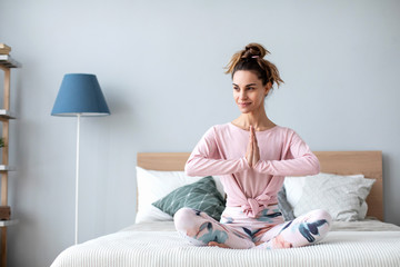 Woman yoga in the lotus position at home on the bed.