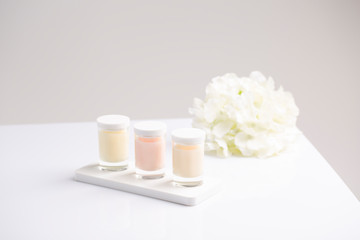 three jars of skincare candle cream with natural fresh summer flowers