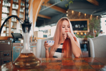 Young pretty girl drinks hot coffee in cafe.
