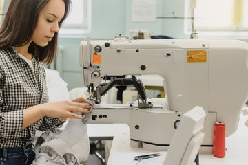 close up photo of a young woman sewing with sewing machine in a factory