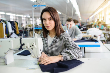 close up photo of a young woman sewing with sewing machine in a factory