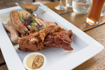 Meat platter with roasted meat, sausages, mustard seeds sauce and glass of beer
