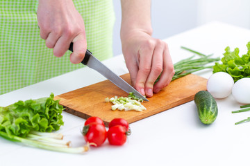 Cooking woman in apron chopping eco friendly products for fresh healthy vegetables salad in the kitchen at home. Diet and clean food. Preparation for vegetable dishes