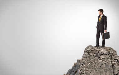 Young business person on the top of the rock with copy space
