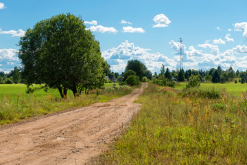 Rural country road through the field to the village