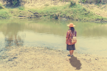 Sad woman standing alone, waterfront loneliness.