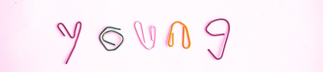 paper clip bend to the word love, young, proud, and labor  with light associate with the proud parade. celebrating the coming of May.