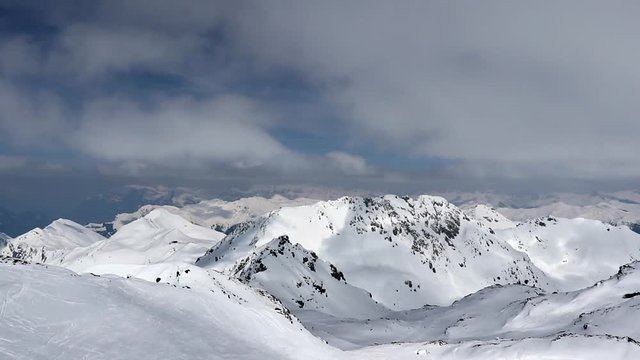 Time lapse of clouds moving over snow mountains and tiny skiers riding down the slope on rothorn in lenzerheide.