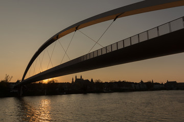 Sunset in downtown Maastricht seen from the riverside with a view on the historic skyline with silhouette of the churches and hoge brug (high bridge)