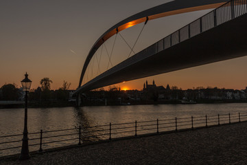 Sunset over the river Maas with the silhouette of the churches in the old city in downtown Maastricht