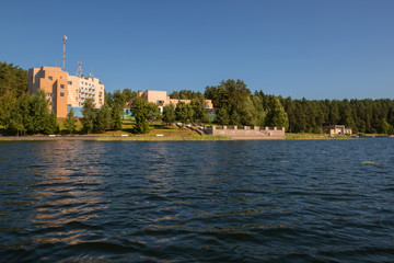 Fototapeta premium Building on the shore of a forest lake on a summer day