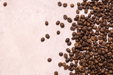 Roasted coffee beans in bulk on a light pink background. dark cofee roasted grain flavor aroma cafe, natural coffe shop background, top view from above, copy space