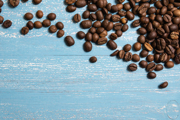 Roasted coffee beans in bulk on a blue wooden background. dark cofee roasted grain flavor aroma cafe, natural coffe shop background, top view from above, copy space