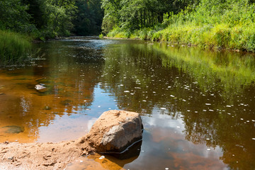 A large boulder lies in the water of the Polomet River, Novgorod Region, Russia