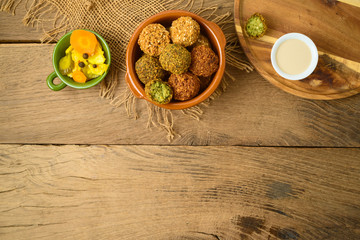 Falafel balls with tahini sauce on wooden board. Top view from above