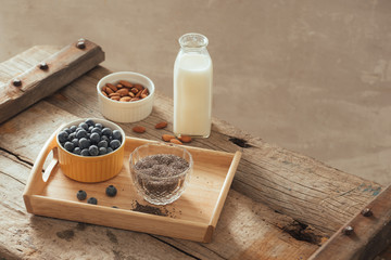 Fresh blueberries, almond and chia seeds with milk on wooden board. Ideal healthy breakfast concept.