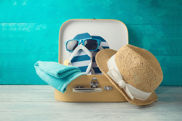 Summer concept background with cute funny flip flops, suitcase and hat on wooden table
