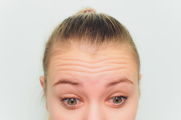 Doctor giving face lifting injection on mid age woman in the forehead between eyebrows to remove...