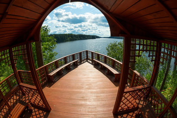 Gazebo in the shape of the nose of the ship on the shore of a forest lake