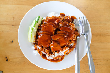 Red pork with rice and cucumber on a plate.