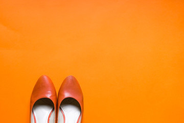 Funky orange high heels flat lay on orange background