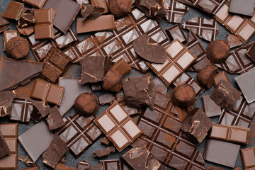 Dark or milk organic chocolate pieces, cocoa powder and truffle candies on dark concrete backgound