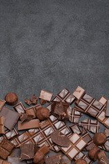 Dark or milk organic chocolate pieces, cocoa powder and truffle candies on dark concrete backgound