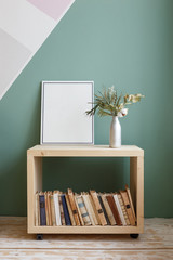 Green plant with a white flower on a bookcase with old books and a frame with a copy space on it....