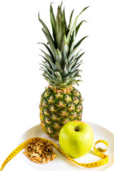 Diet, healthy food, vitamins, fitness diet food concept. Pineapple, apple, nuts on a plate isolated on white background