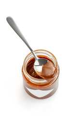 Spoon of homemade chocolate caramel sauce on jar isolated on white
