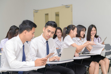 Teenage Students in uniform working with laptop in classroom
