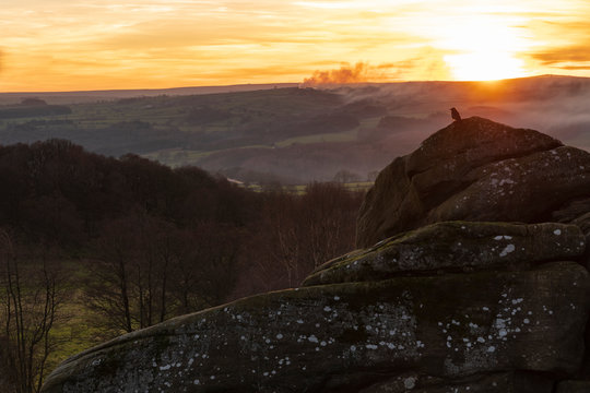With smoke in the air the sun is setting over the Pennines near Pateley Bridge close to Brimham Rocks