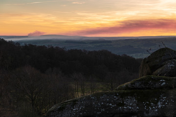 With smoke in the air the sun is setting over the Pennines near Pateley Bridge close to Brimham Rocks