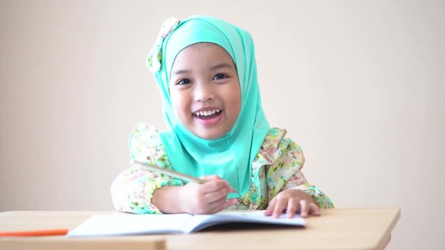 Muslim kid doing homework and reading a book. Kid enjoy learning with happiness at home. Clever,Education and smart learning concept. (Video Slow motion).
