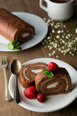 Delicious chocolate roll sponge cake with vanilla cream and mint leaves. Desert sweet food.