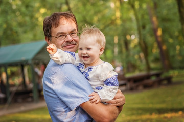 Baby in a Ukrainian blouse with dad for a walk in the summer Park.