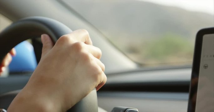 Woman driving car - close up on hands holding steering wheel